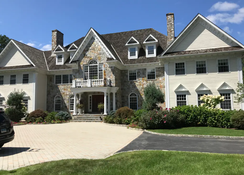 Large stone and white-sided home after an exterior repaint